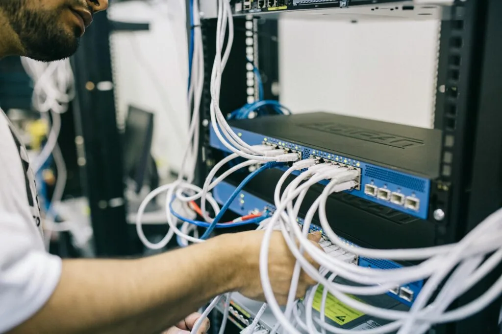 pexels-photo-442150-442150 An IT professional configuring network cables in a server rack, focusing on Ethernet connections.
